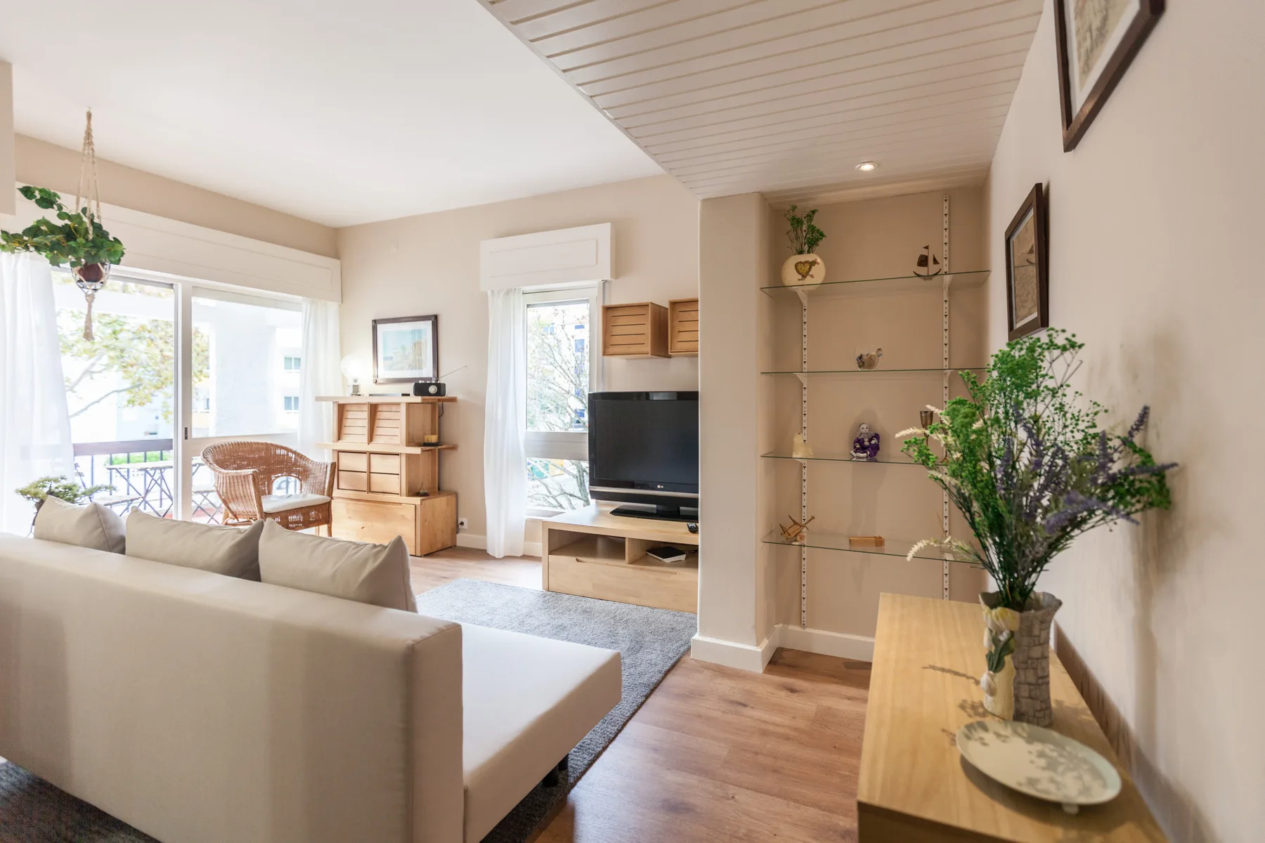 Living room with seating, a television, and windows opening onto a balcony.