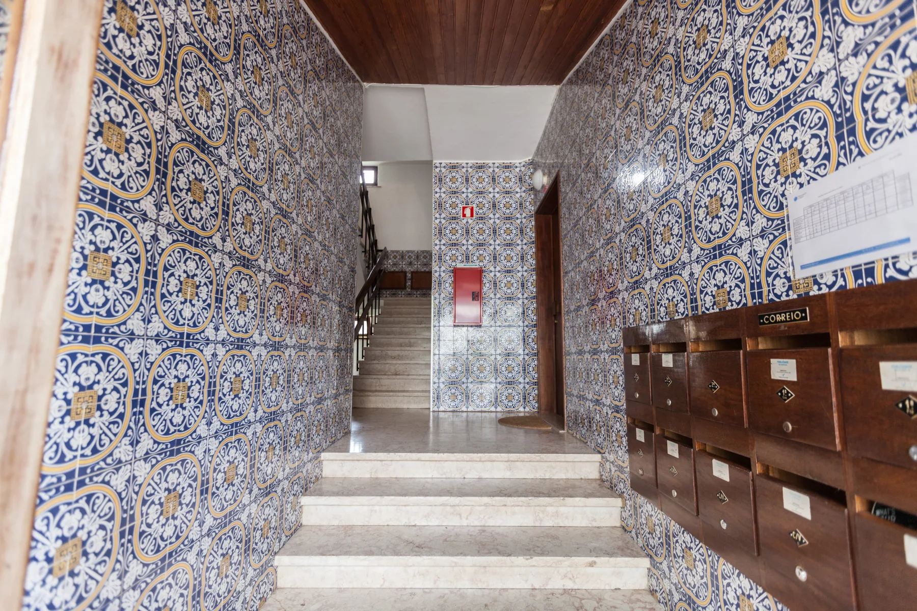 A tiled entrance hallway with marble steps and wooden mailboxes.