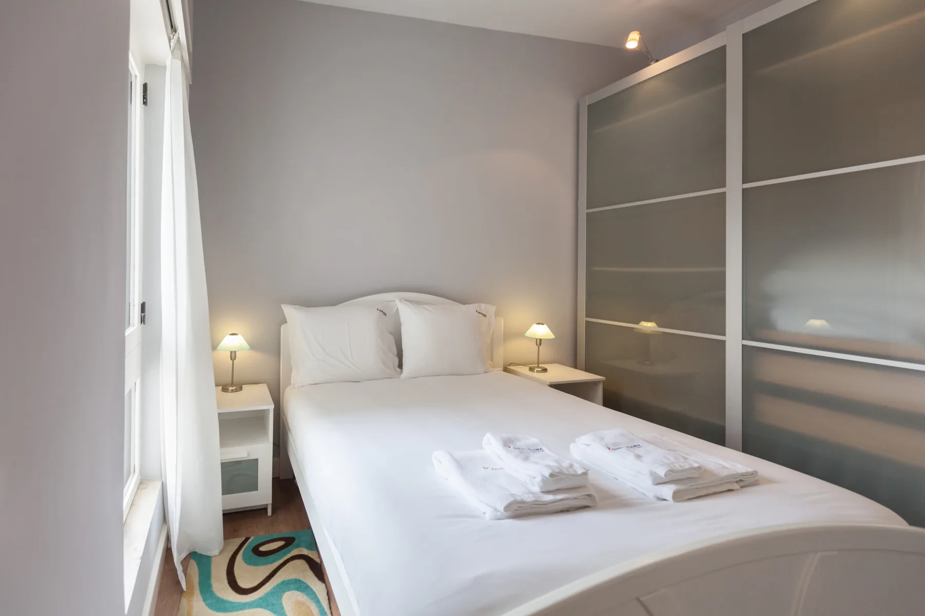 A bedroom with a neatly made bed and bedside lamps.