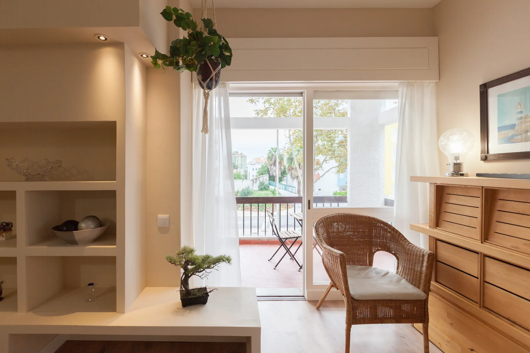 A bright living area opens onto a balcony through glass doors.