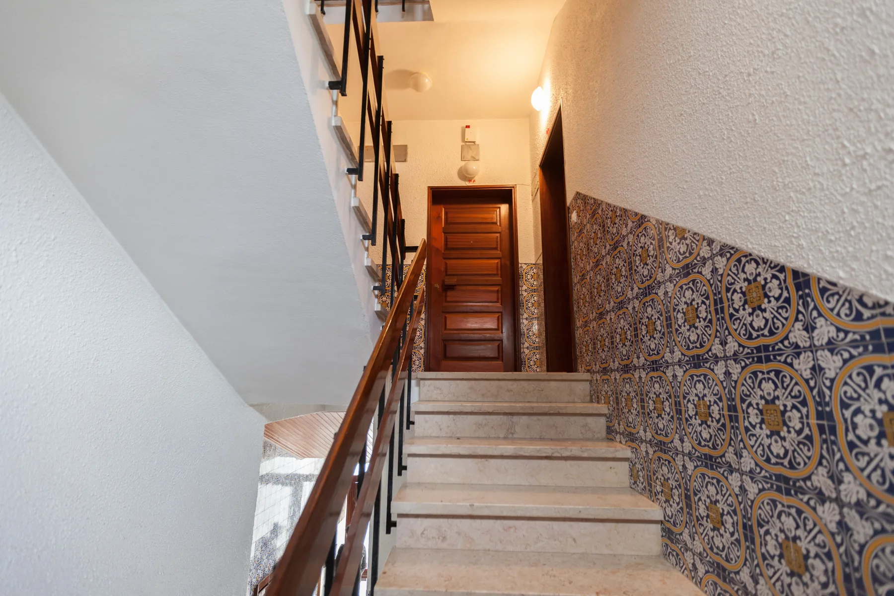 A tiled interior staircase leads up to a wooden door.
