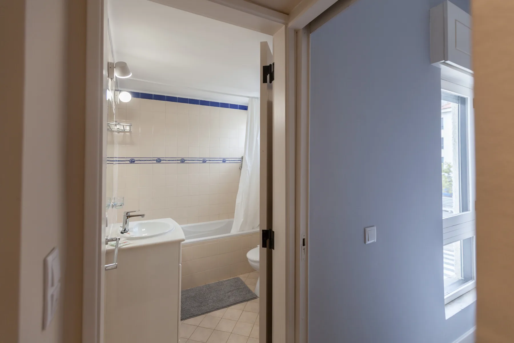 A bathroom with a bathtub and sink is visible through an open doorway.