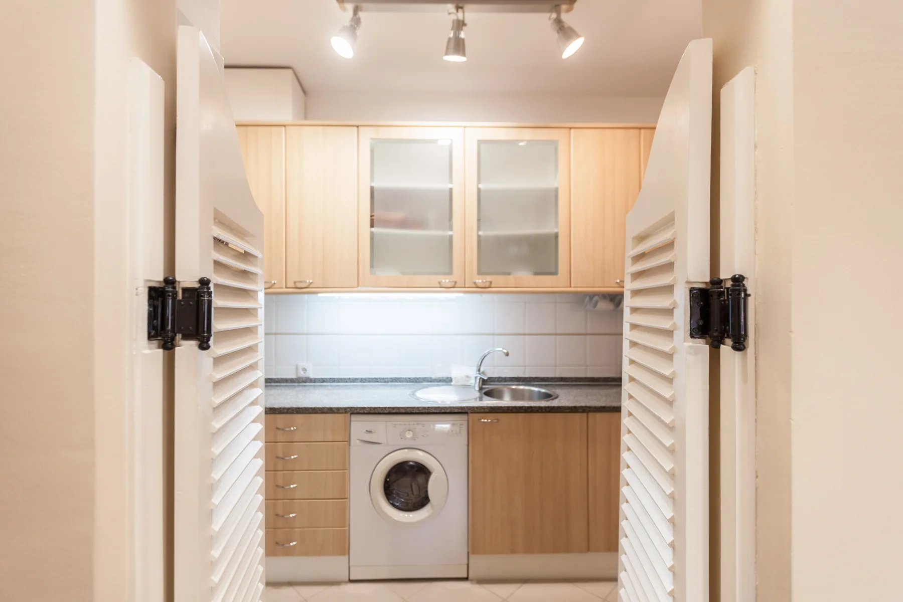 A compact kitchen with cabinets, a countertop, and a washing machine.