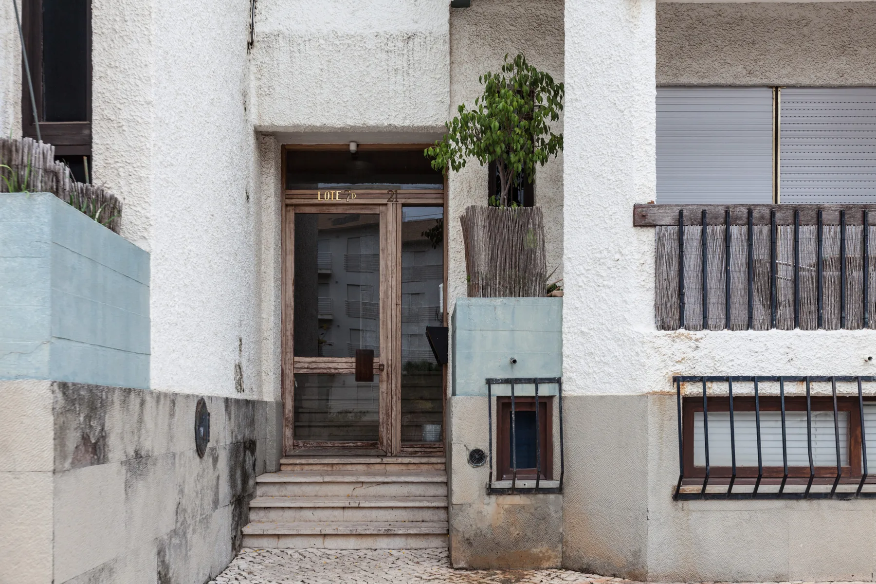 Building entrance with glass doors, steps, and barred windows.