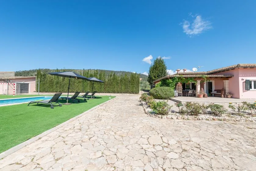 An outdoor pool area with lounge seating beside a stone-paved courtyard.