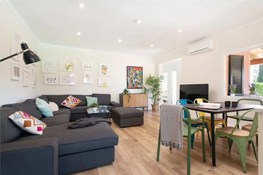 A bright living and dining room with sectional seating and a table.