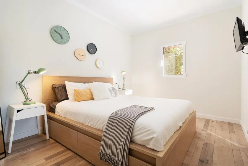 A bright bedroom with a wooden bed and white bedding.