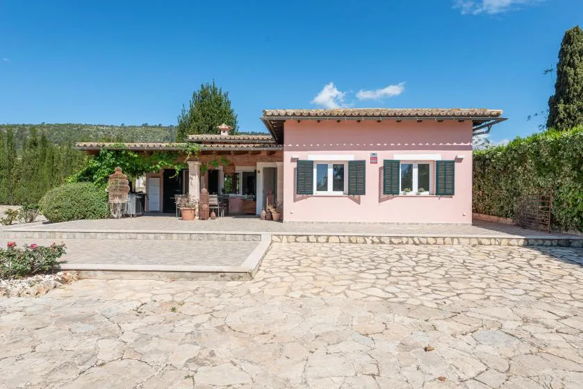 A pink house faces a broad stone-paved courtyard.