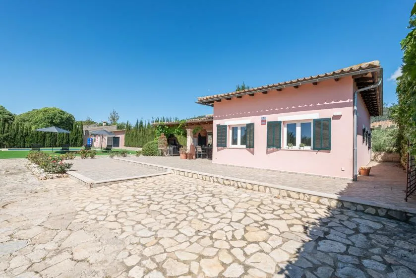 A pink house stands beside a broad stone-paved courtyard.