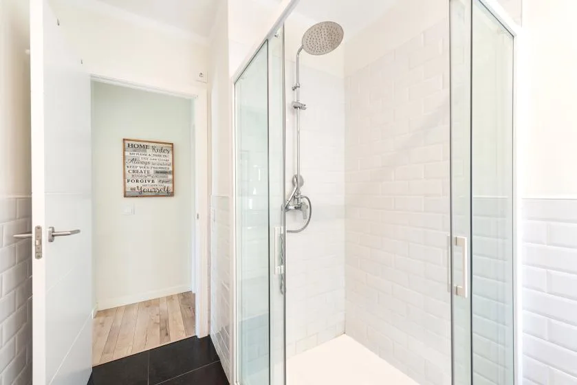 A bright bathroom with a glass-enclosed shower and a doorway.