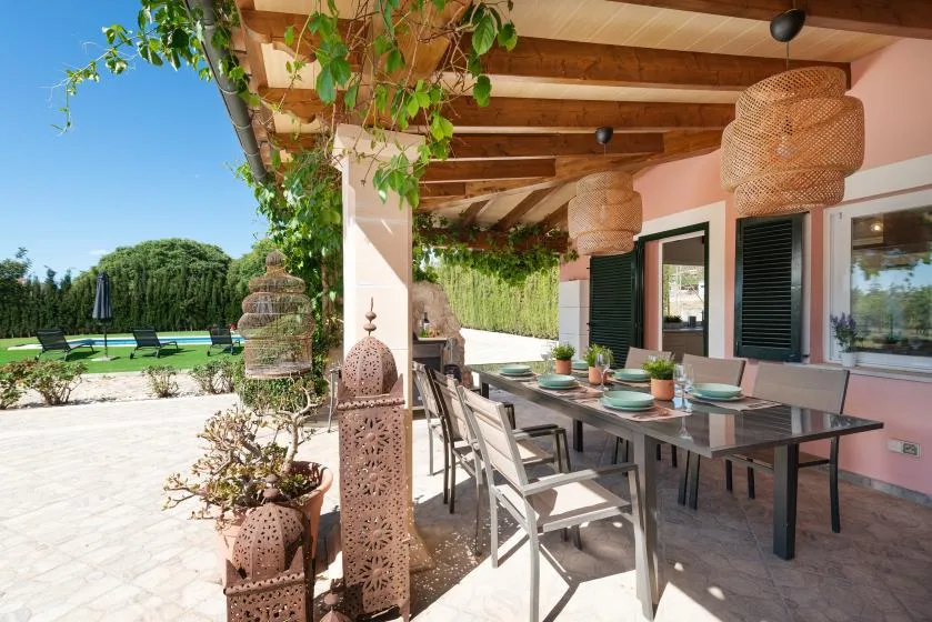 A covered outdoor dining area with a long table beneath a wooden pergola.