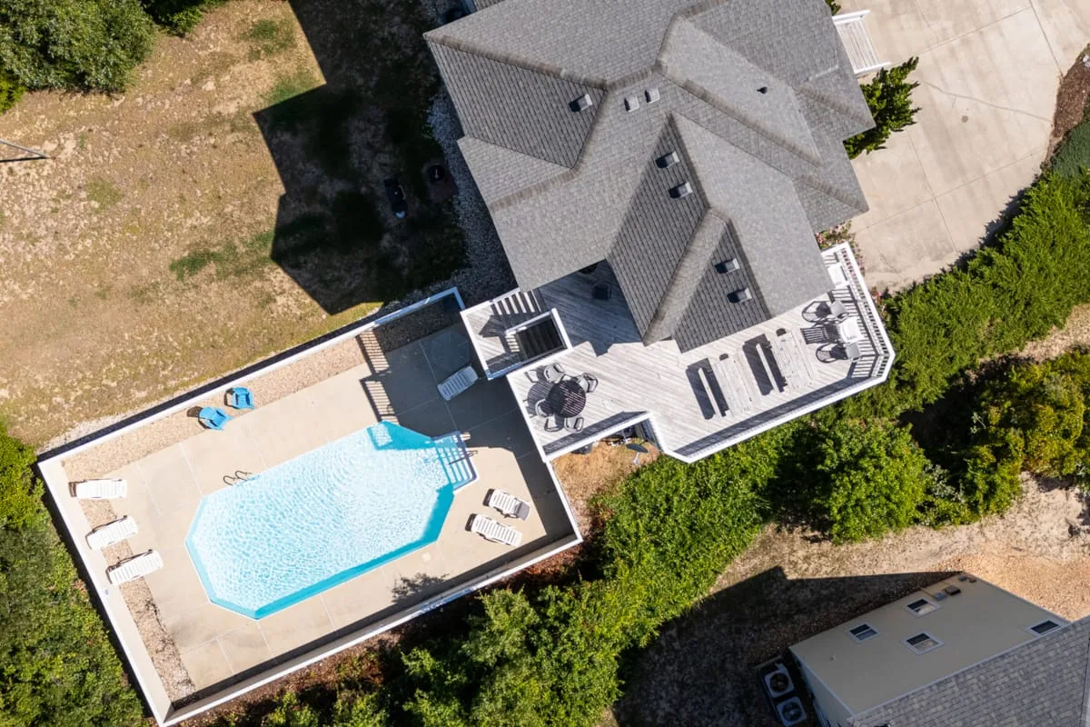 Vista aérea de una casa, una piscina y vegetación alrededor.