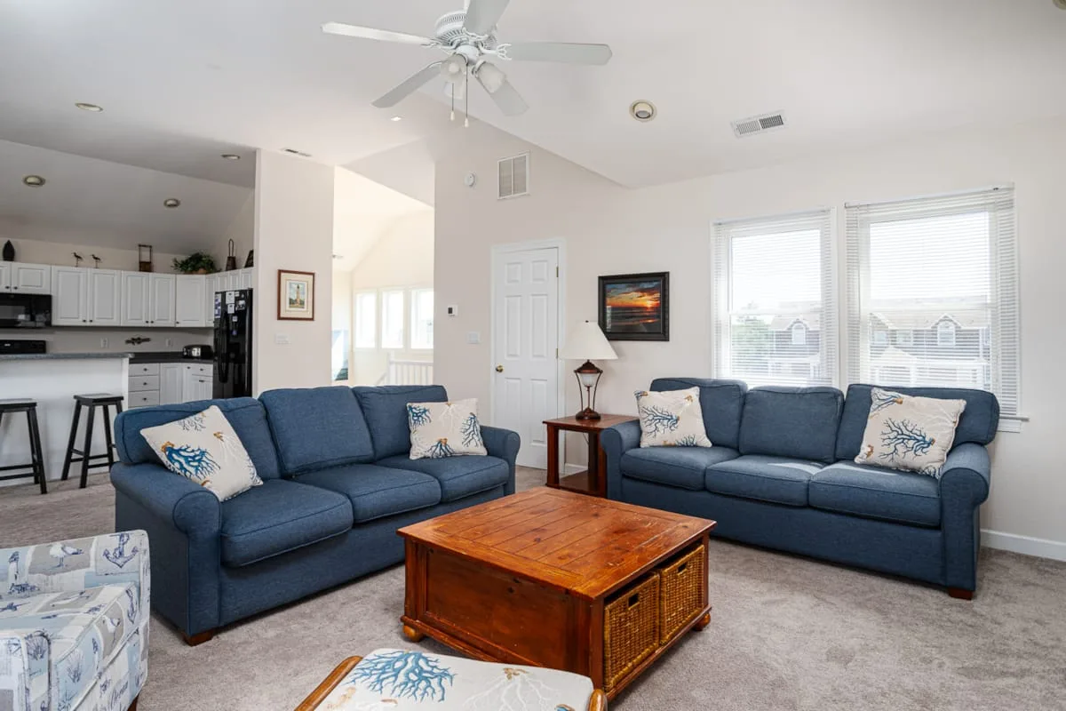 A bright living room with blue seating and a wooden coffee table.