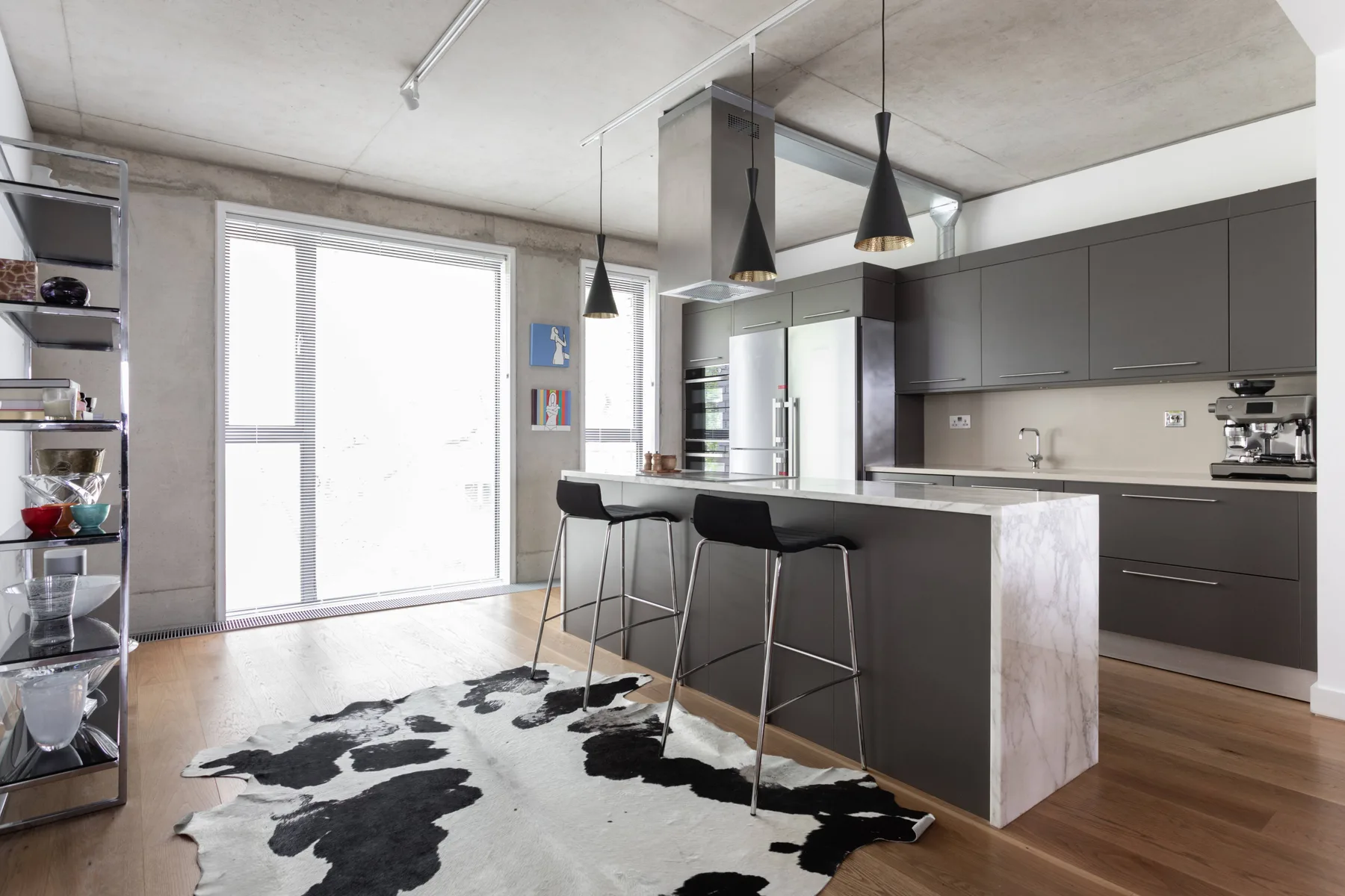 A modern kitchen with a central island, bar seating, and pendant lights.