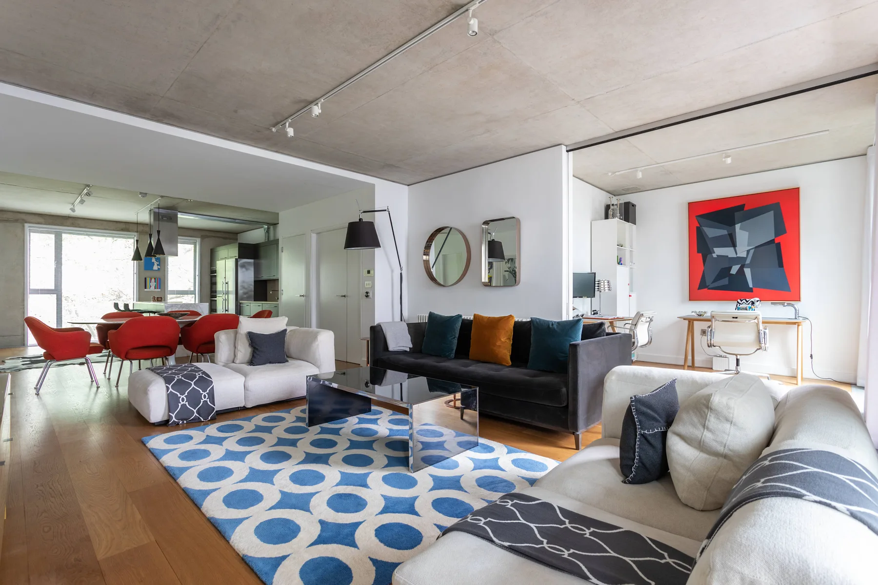 A modern living room with seating arranged around a blue patterned rug.