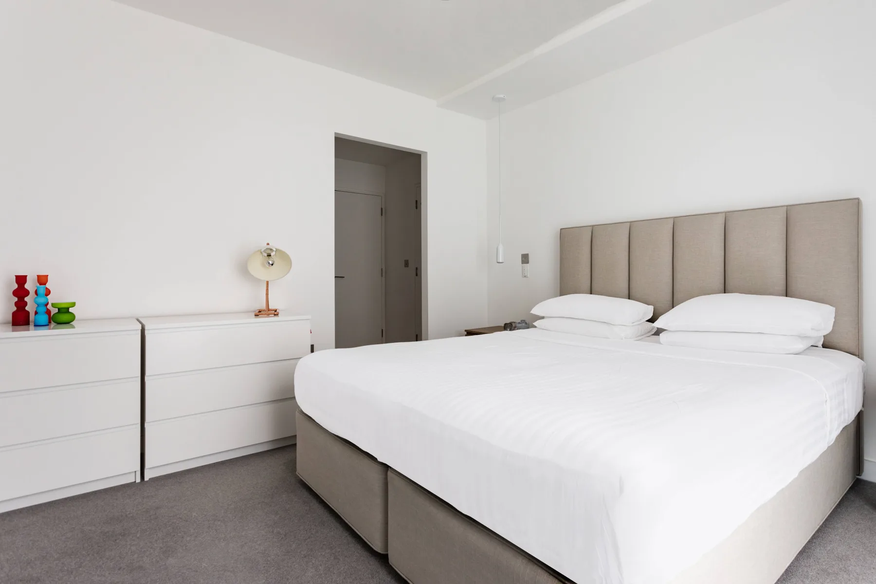 A bright bedroom with a neatly made bed and a white dresser.