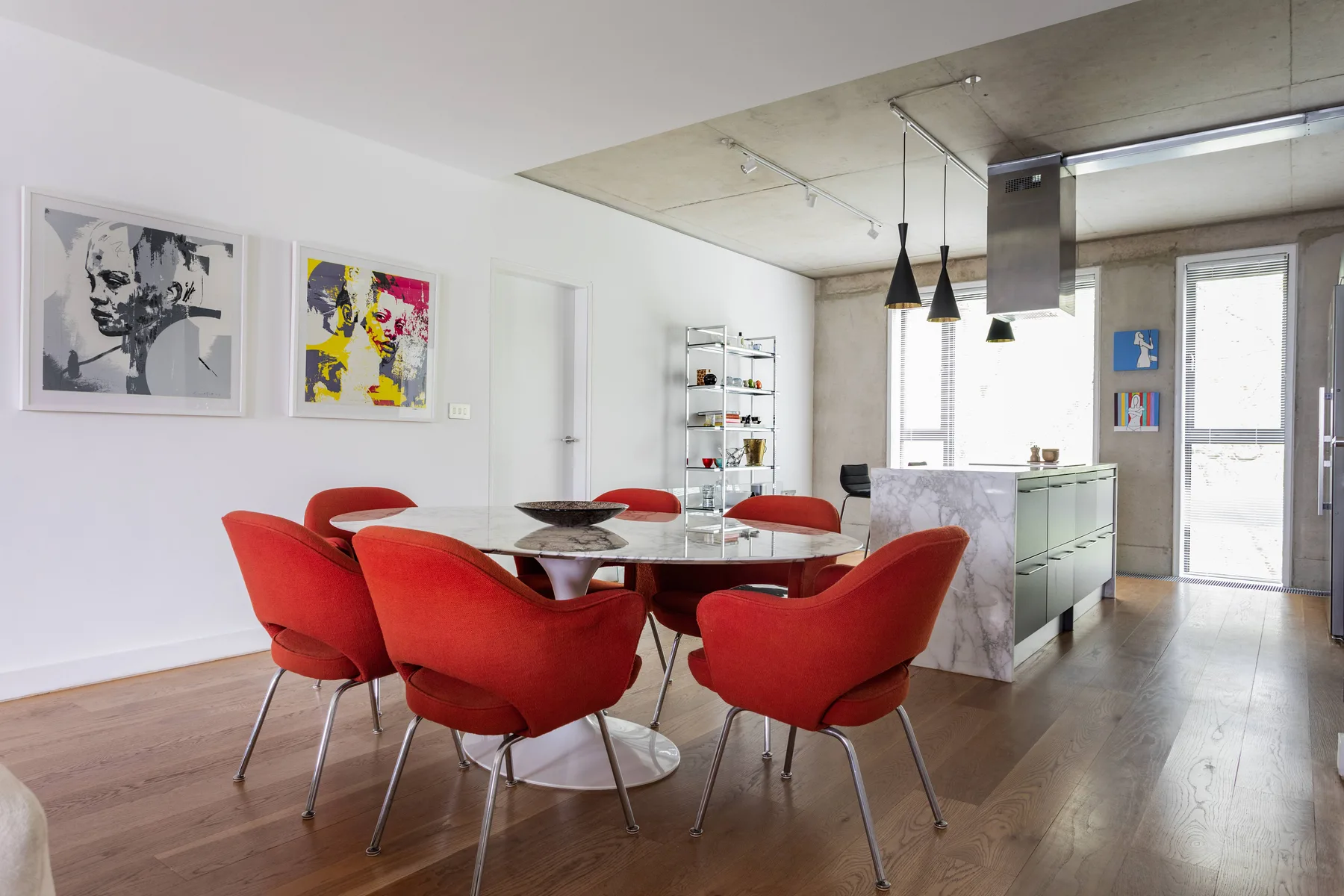 A dining area with red seating beside a bright kitchen.