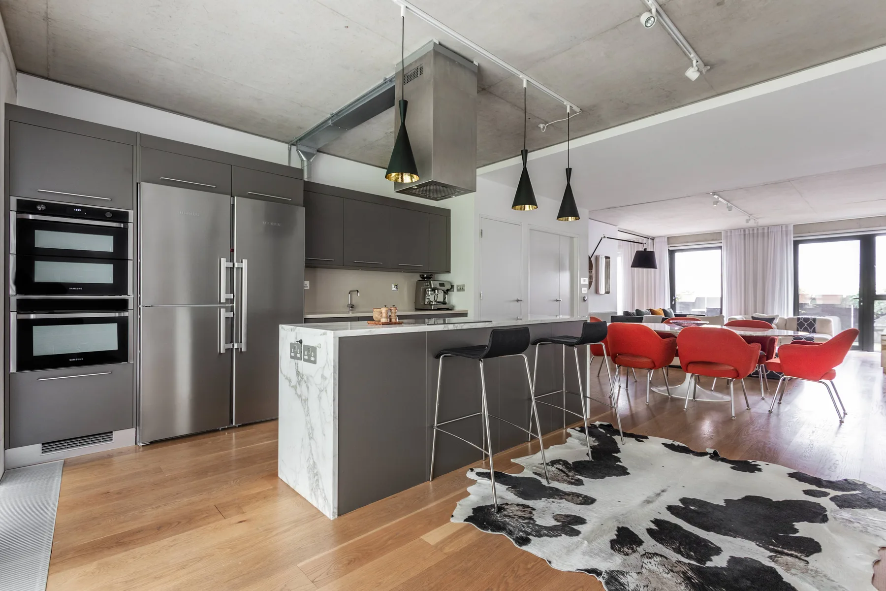 An open-plan kitchen and dining area features a kitchen island and red dining chairs.