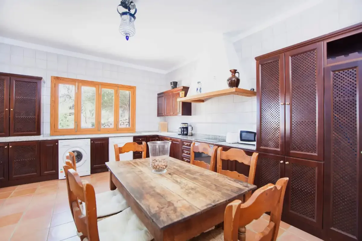 A bright kitchen with wooden cabinets, a dining table, and chairs.