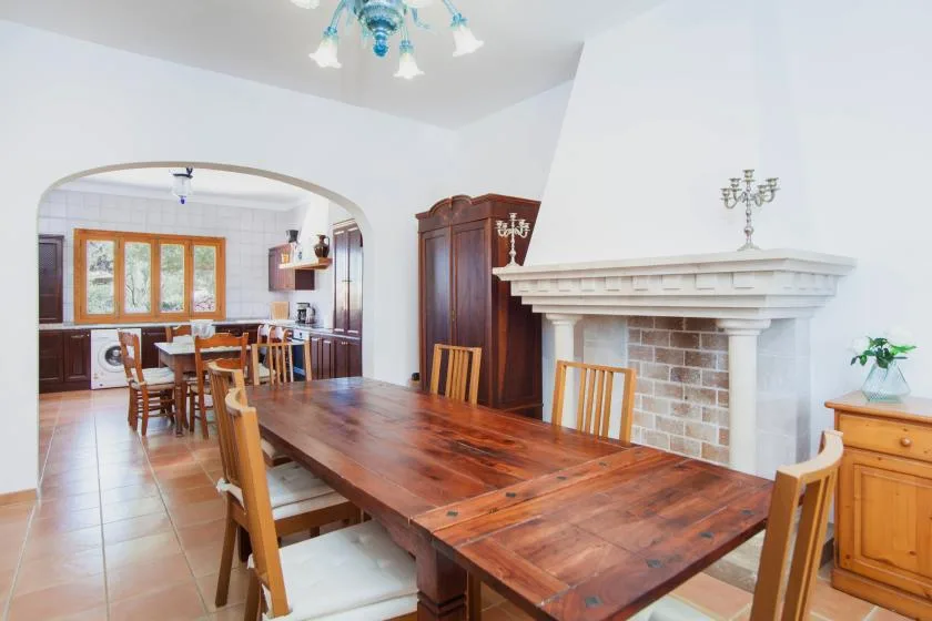 A dining area with a long wooden table beside a brick fireplace.