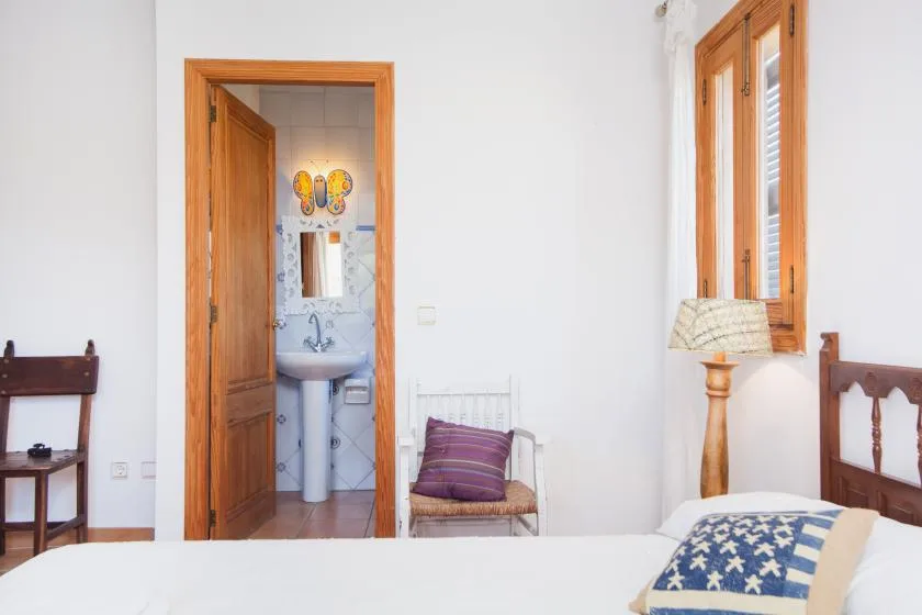 A bright bedroom with a bed and wooden furnishings.