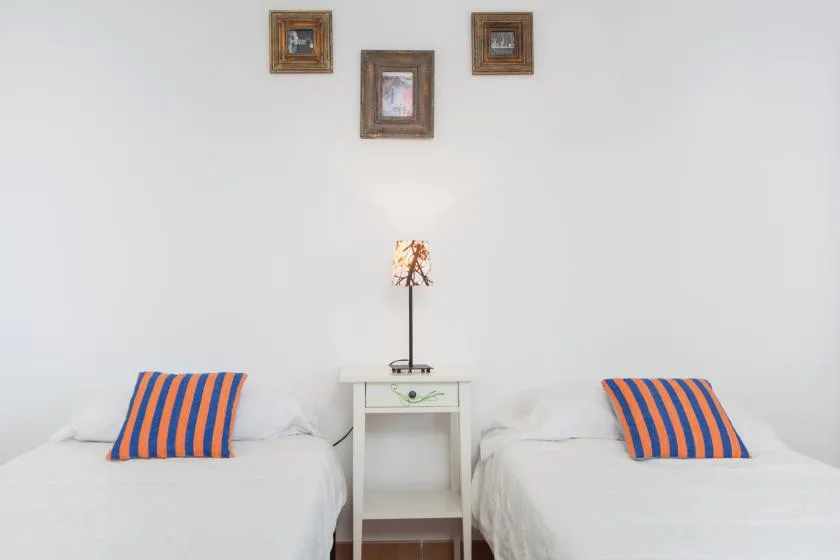 A bright bedroom with two beds and a small table between them.