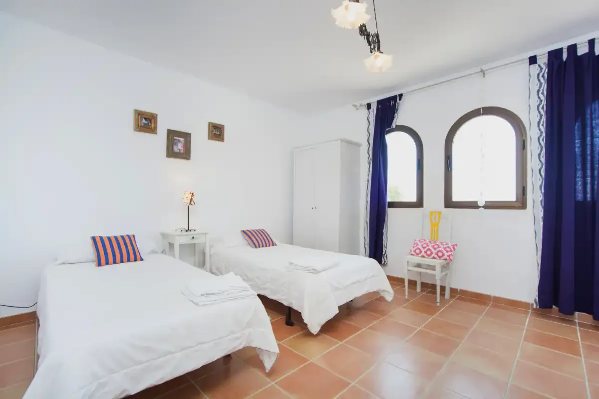 A bright bedroom with two beds and arched windows.