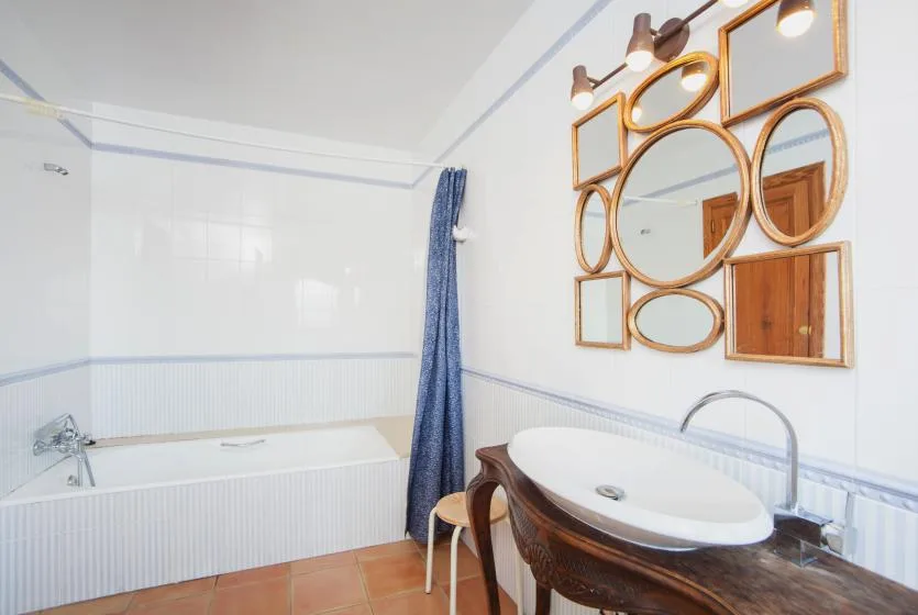 A bright bathroom with a bathtub, a sink, and decorative mirrors.