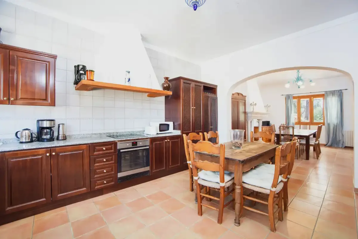 A tiled kitchen opens into a dining area with a wooden table.