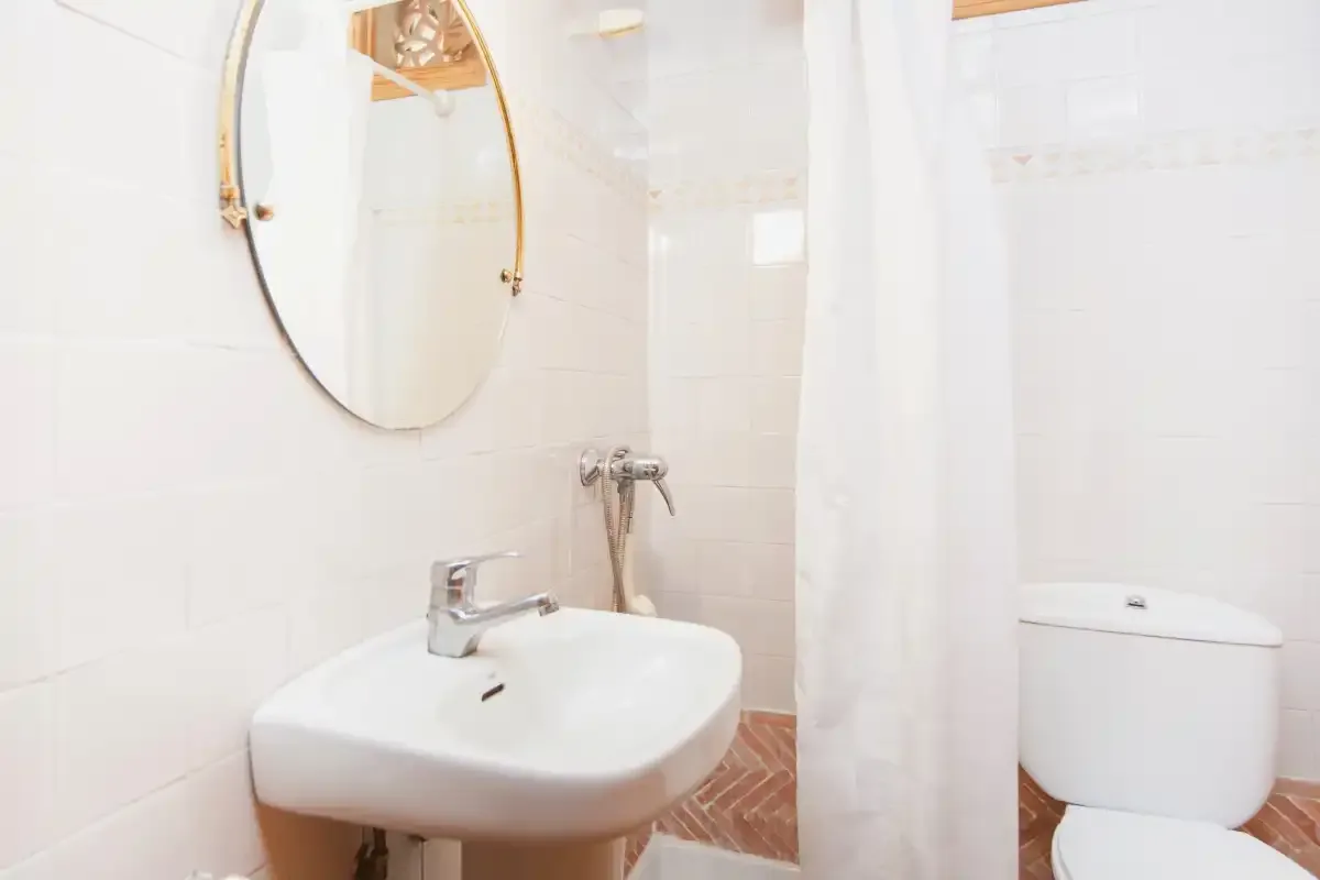 A bright bathroom with a sink, mirror, and shower curtain.