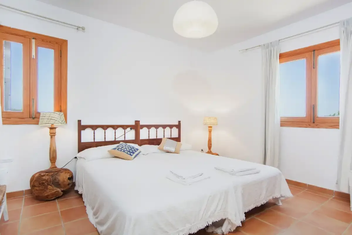A bright bedroom with a bed and two windows.