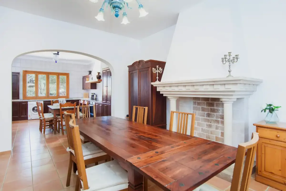 A dining room with a large wooden table and a fireplace.