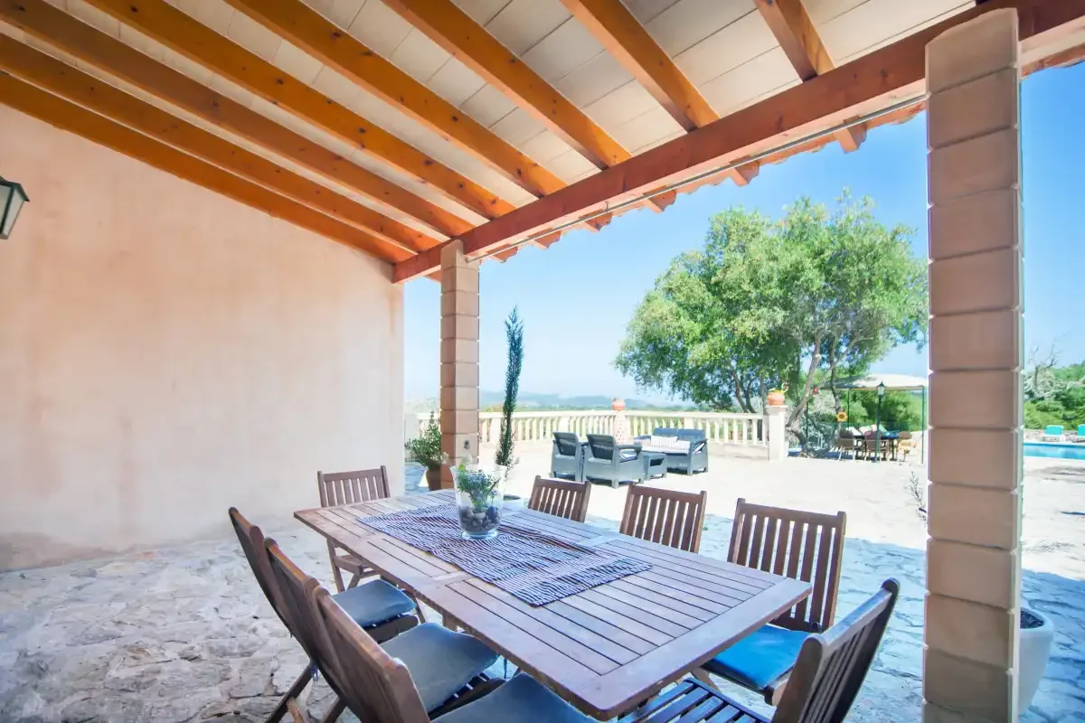 A covered outdoor dining area with a long table and wooden seating.