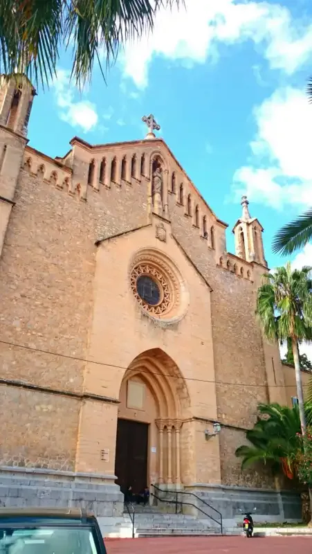 A stone church facade with a round window and an arched entrance.