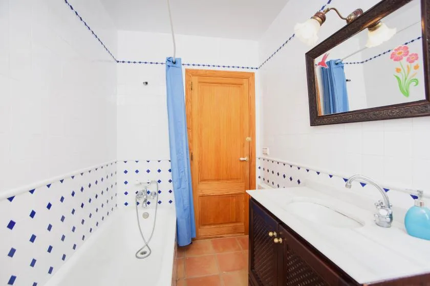 A bathroom with a bathtub, wooden door, and sink vanity.