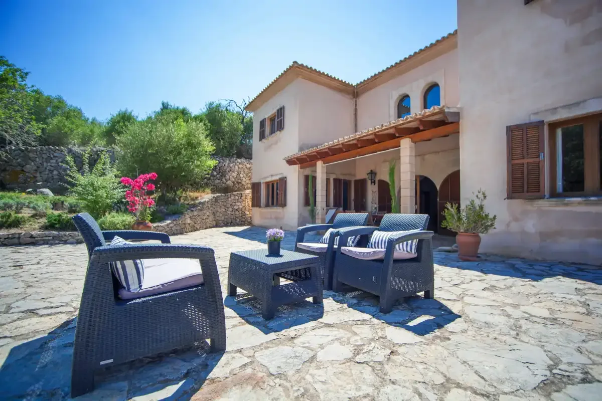 A stone-paved patio with outdoor seating beside a light-colored house.