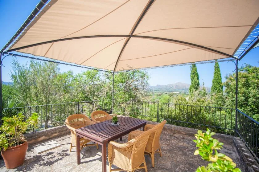 A shaded outdoor dining area with a table and seating beneath a canopy.