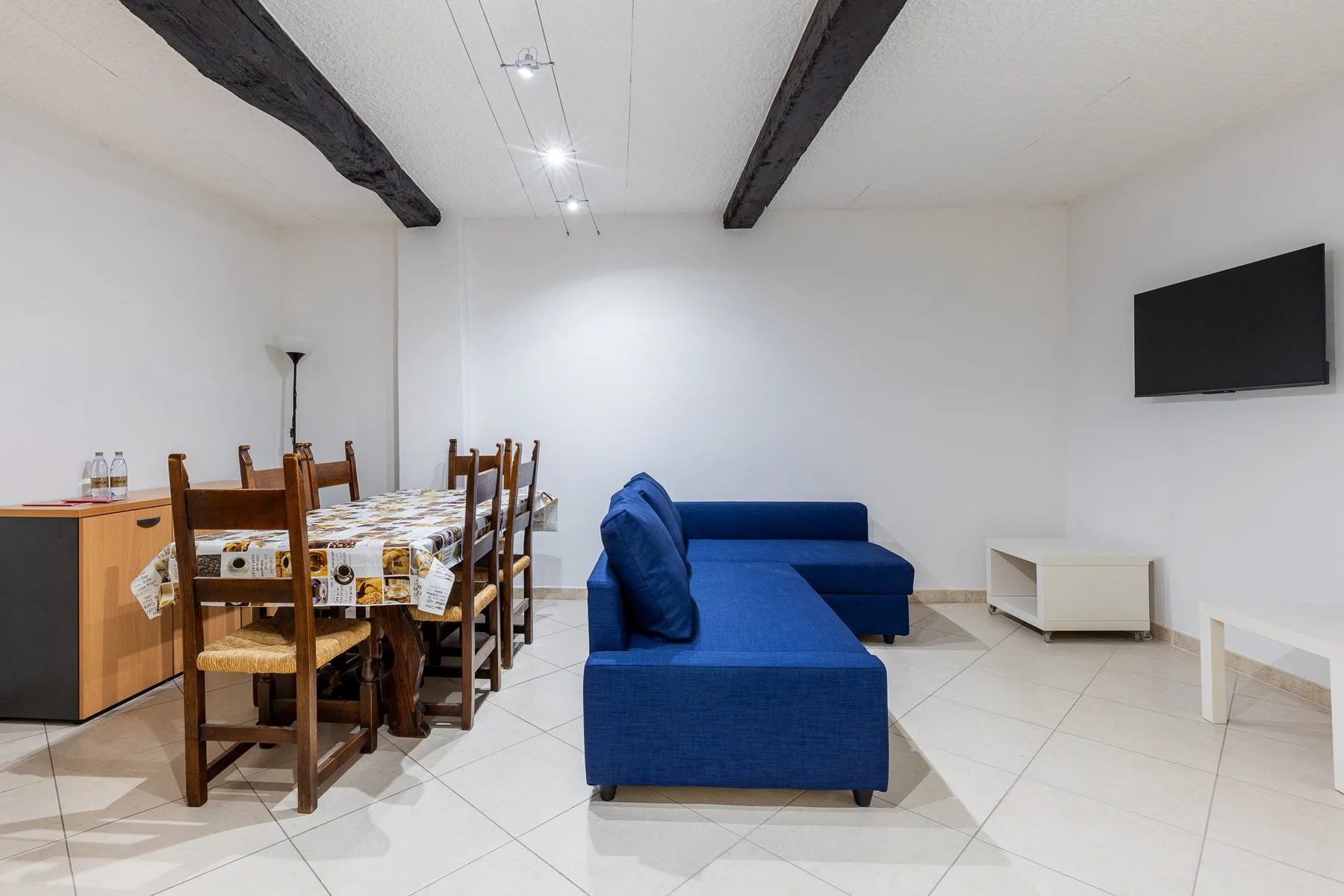Sala de estar con asientos azules junto a una mesa de comedor y sillas.