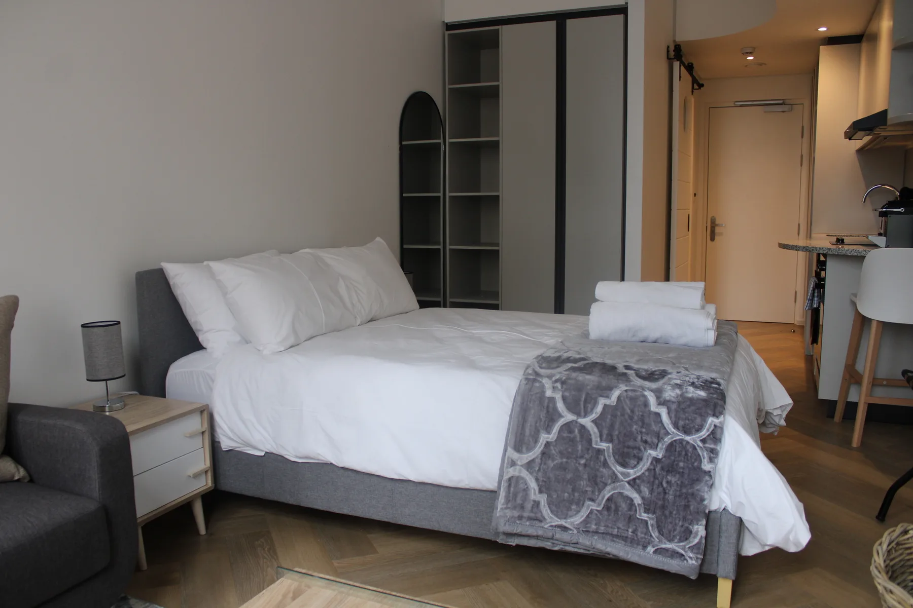 A bedroom with a neatly made bed and folded towels.