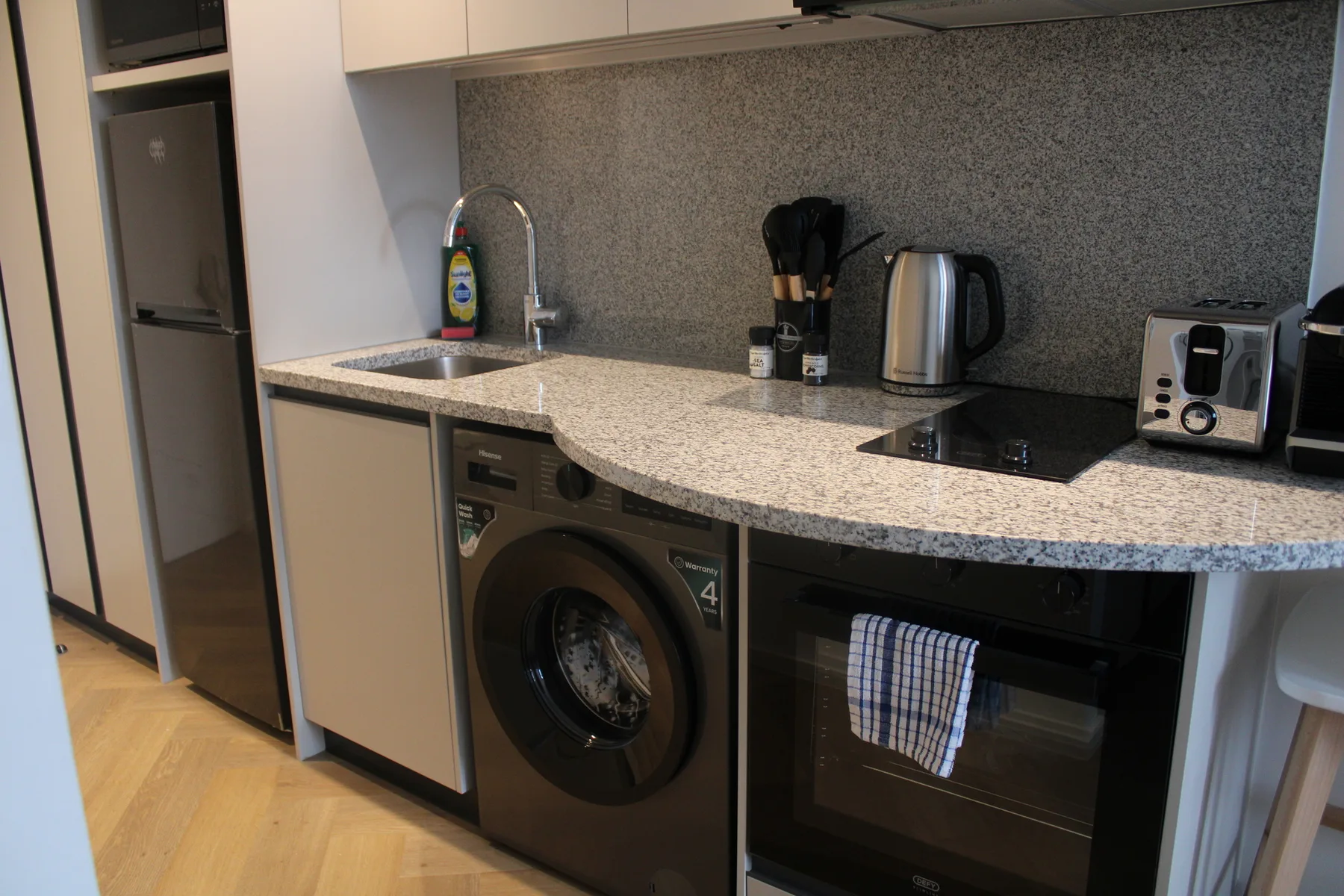 A compact kitchen with a countertop, sink, and built-in appliances.