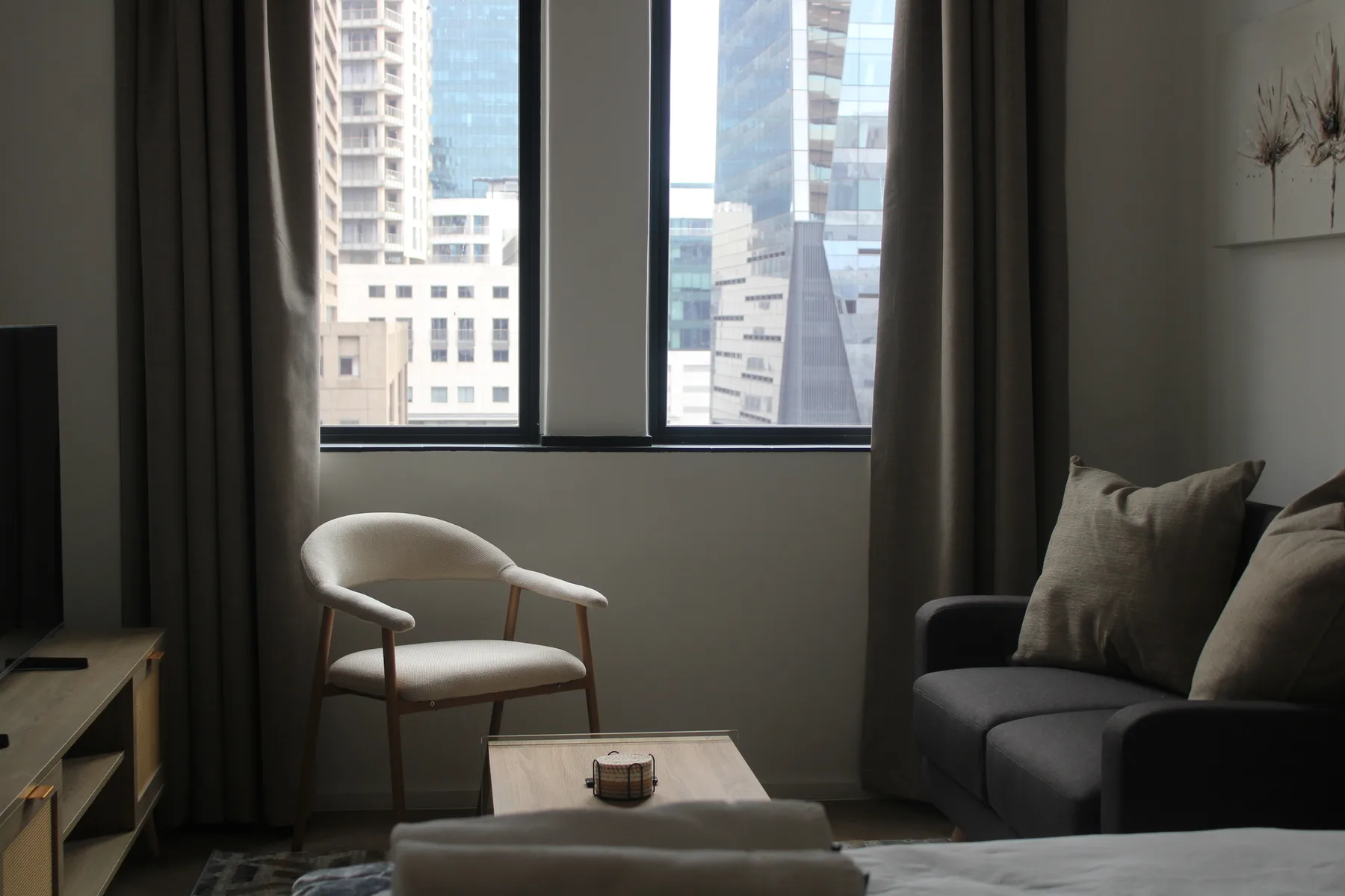 A living room with seating beside a large window overlooking city buildings.