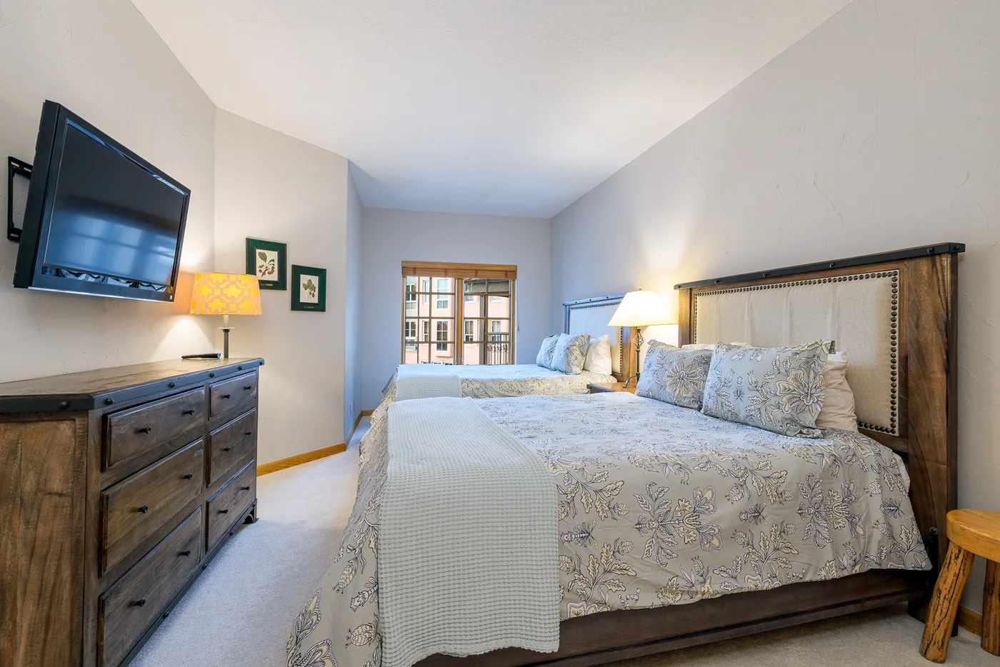 Un dormitorio con dos camas, ropa de cama estampada y una ventana.