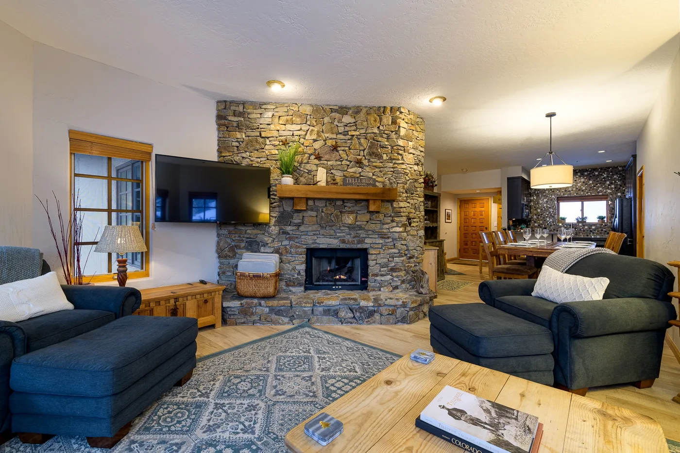 Sala de estar con asientos, una chimenea de piedra y un comedor contiguo.
