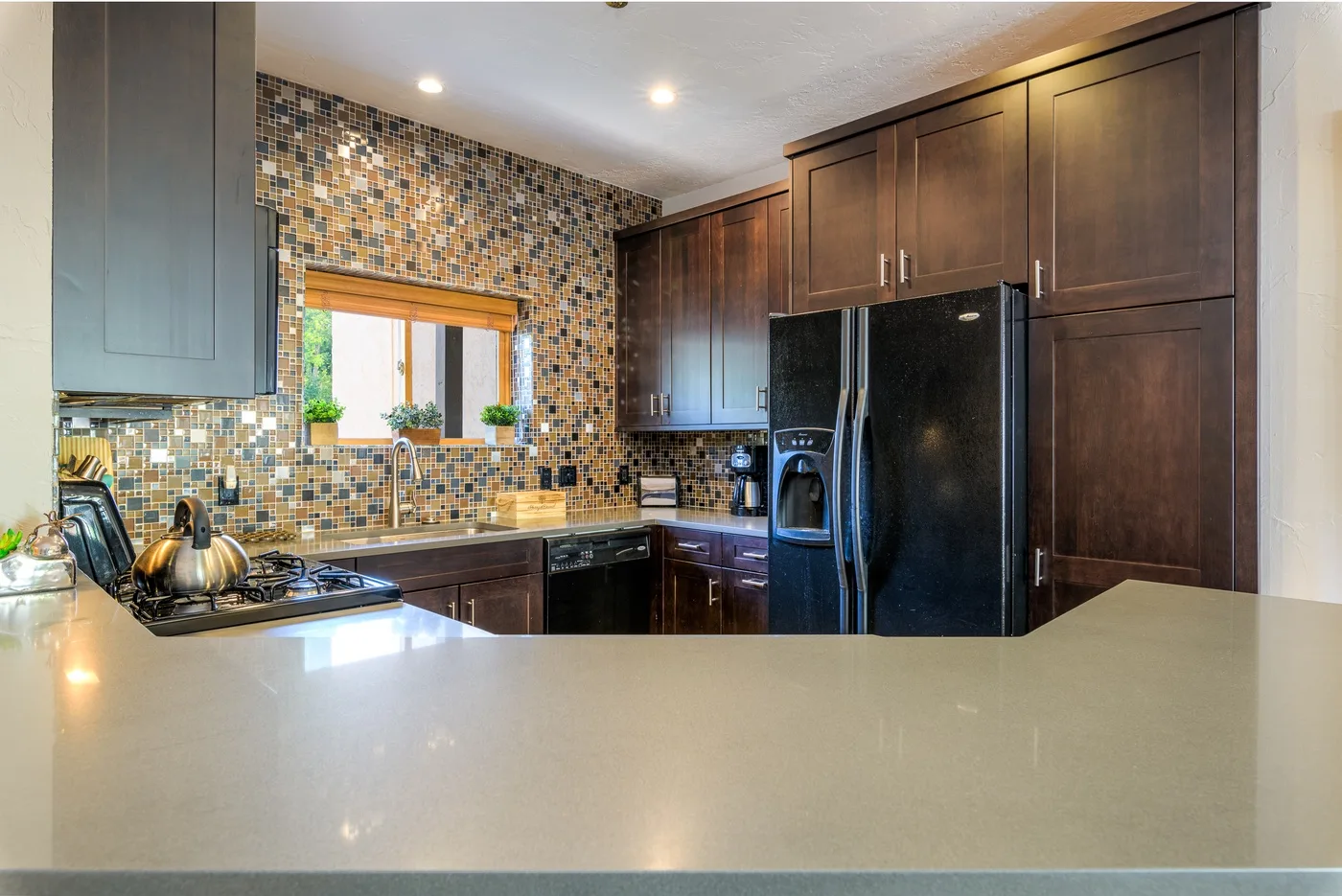 Una cocina con gabinetes oscuros, un salpicadero de azulejos y una amplia encimera en primer plano.