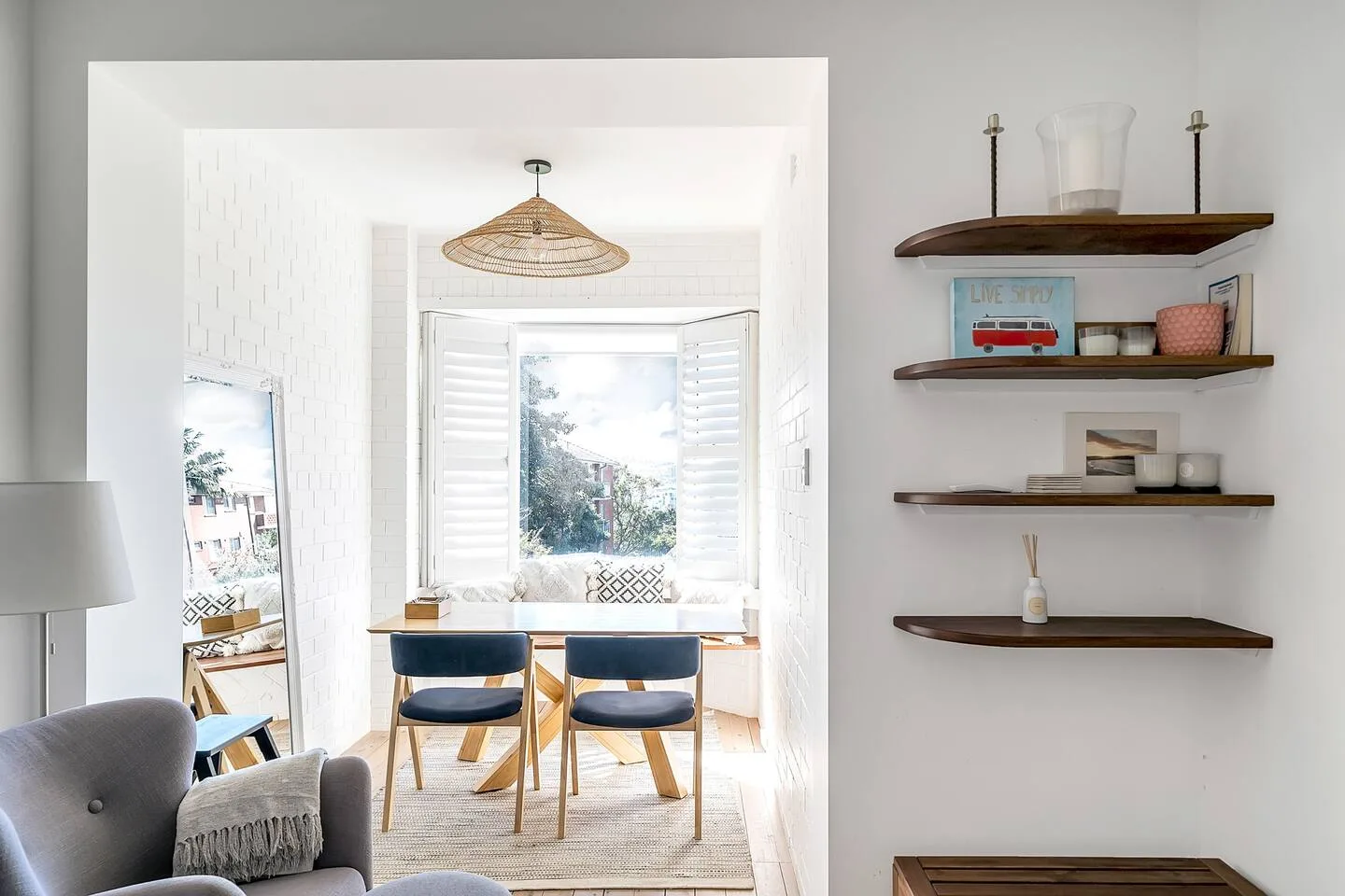 Un luminoso rincón de comedor tiene una mesa y asientos junto a una gran ventana.