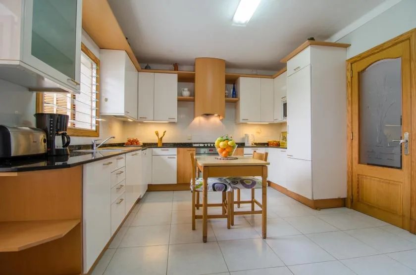 A bright kitchen with white cabinets and a small table in the center.