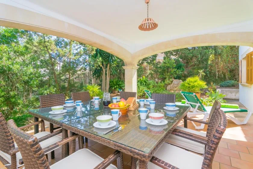 A covered outdoor dining area with a large table and garden views.