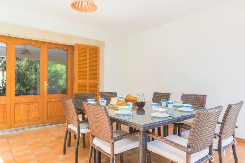 A dining area with a table set with dishes beside wooden doors.