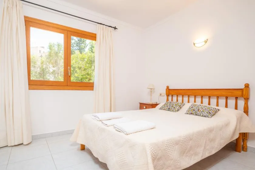 A bedroom with a wooden bed, white bedding, and a window.