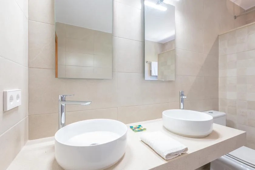 A tiled bathroom with a countertop basin and wall mirrors.